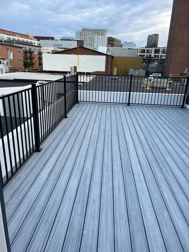 Backyard composite deck with white posts and black baluster railings.