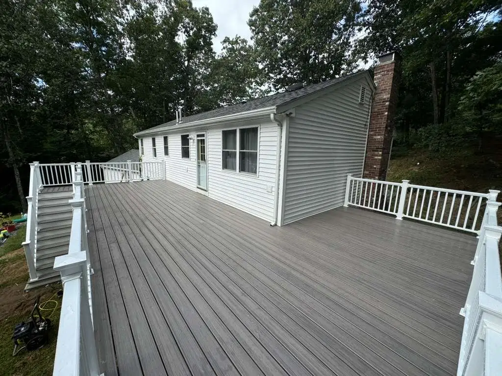Spacious elevated composite deck showing railings and side view of white house.