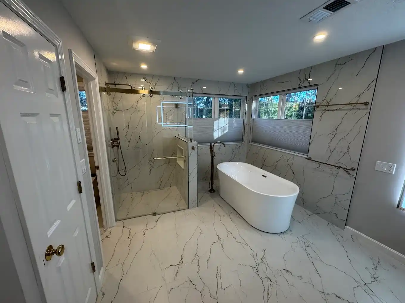 Luxury primary bathroom with freestanding soaking tub and marble wall tiling.