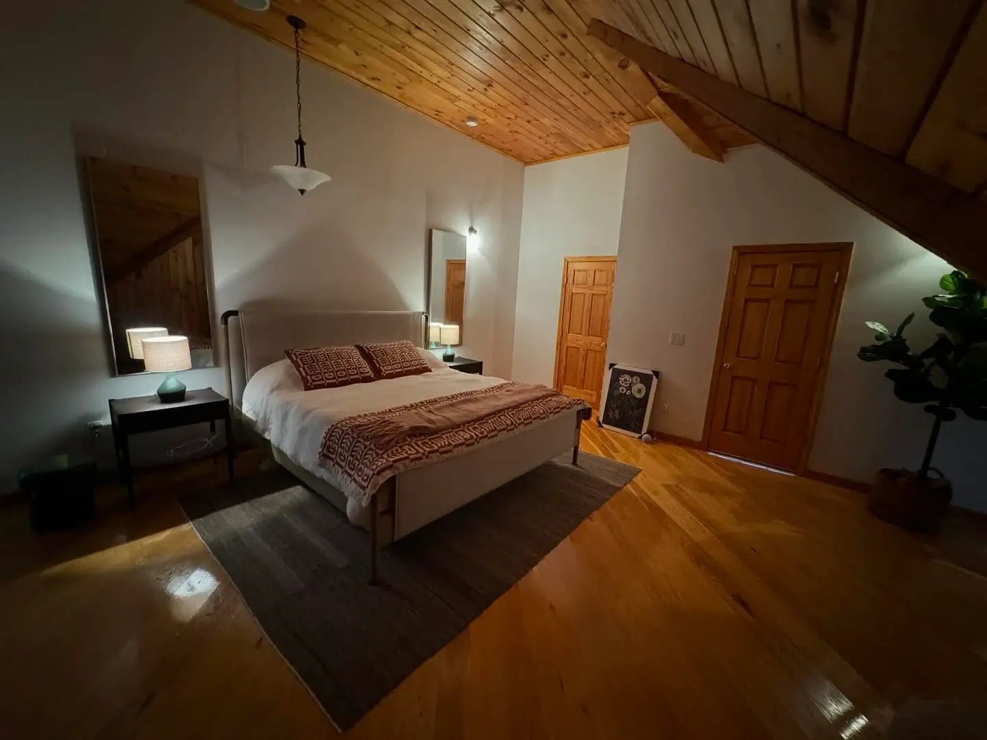 Renovated master bedroom featuring pine vaulted ceiling, wood floors, and natural lighting.
