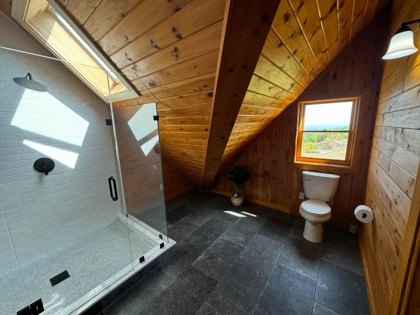 Bathroom with white subway tile walk-in shower, terrazzo floor, and slanted wood ceiling.