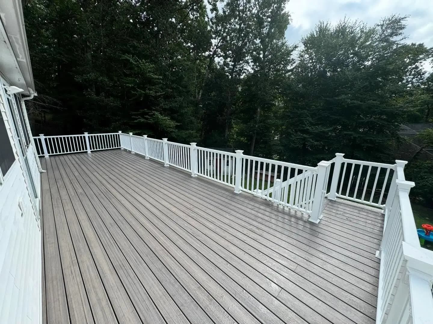 Elevated backyard deck with grey composite decking boards and white railings.