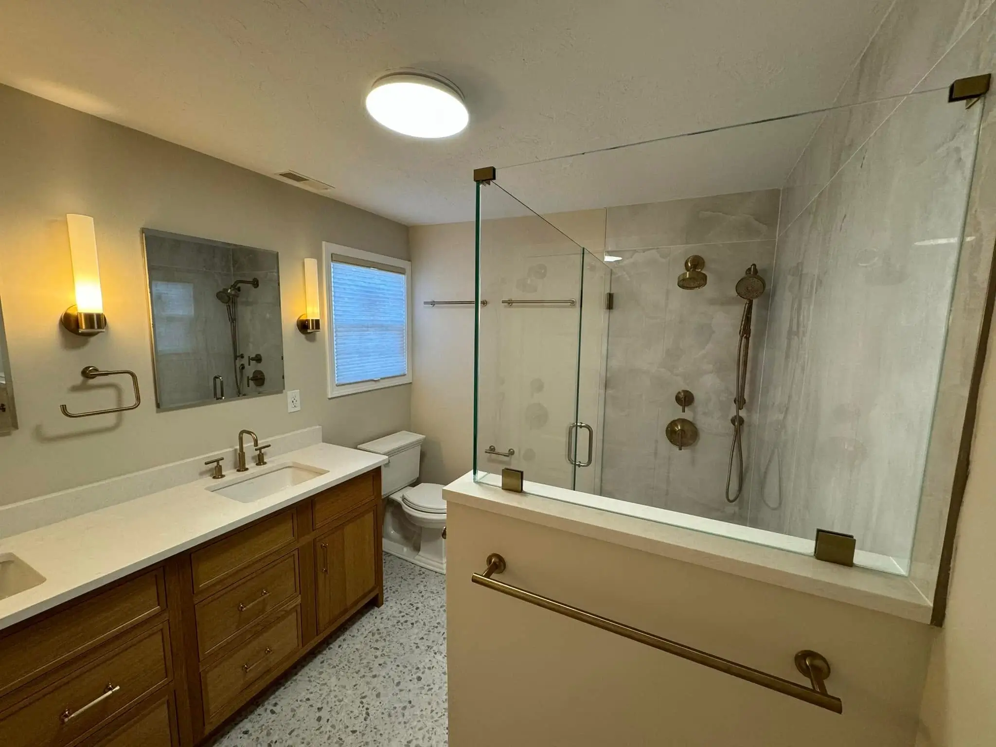 Bathroom remodel detailing double sink vanity, gold hardware, and terrazzo floor tile.