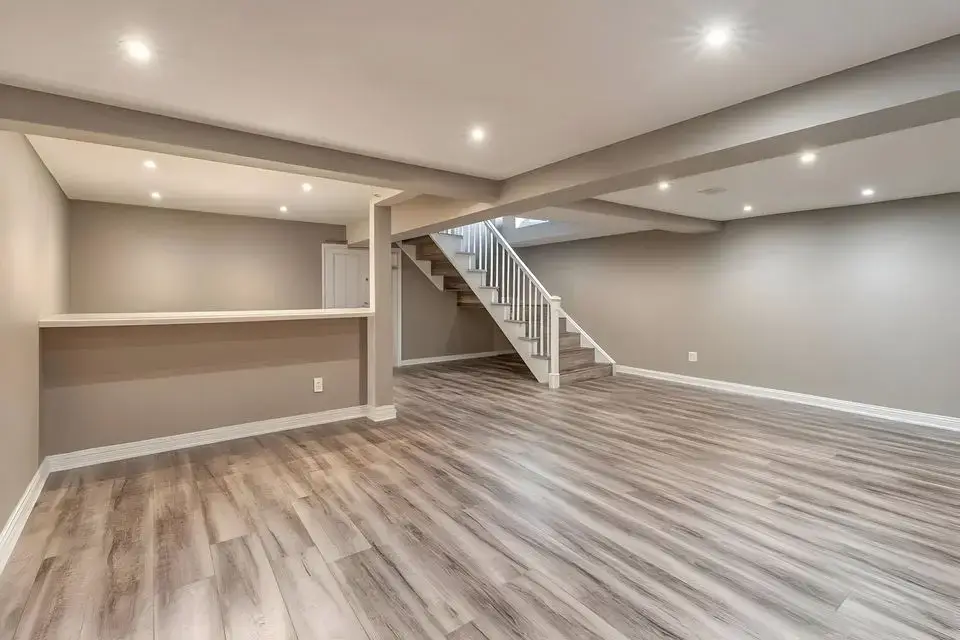 Spacious finished basement remodel with recessed lighting, grey walls, and wood laminate flooring.