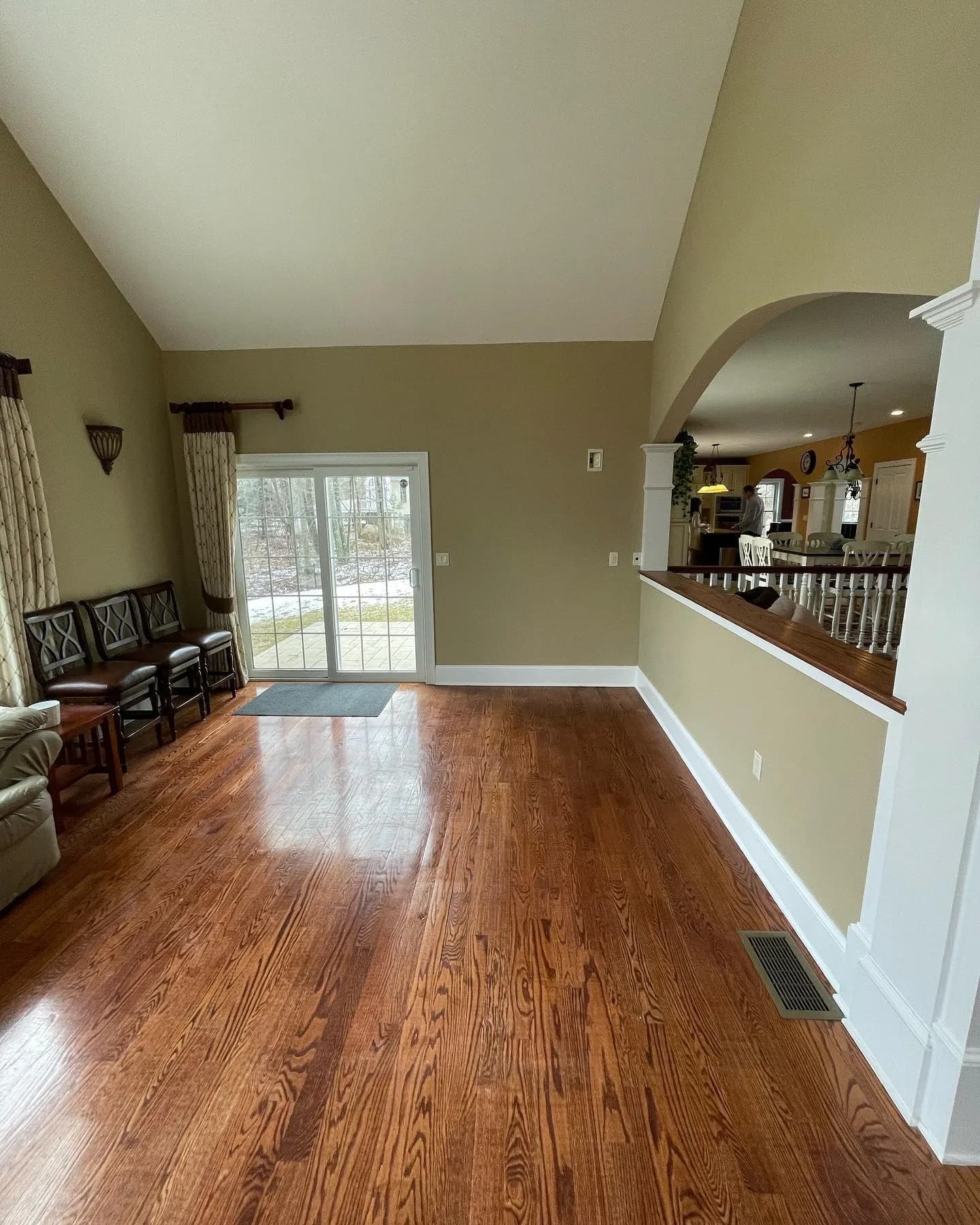 Living room renovation showing wood floors, vaulted ceilings, and archway.