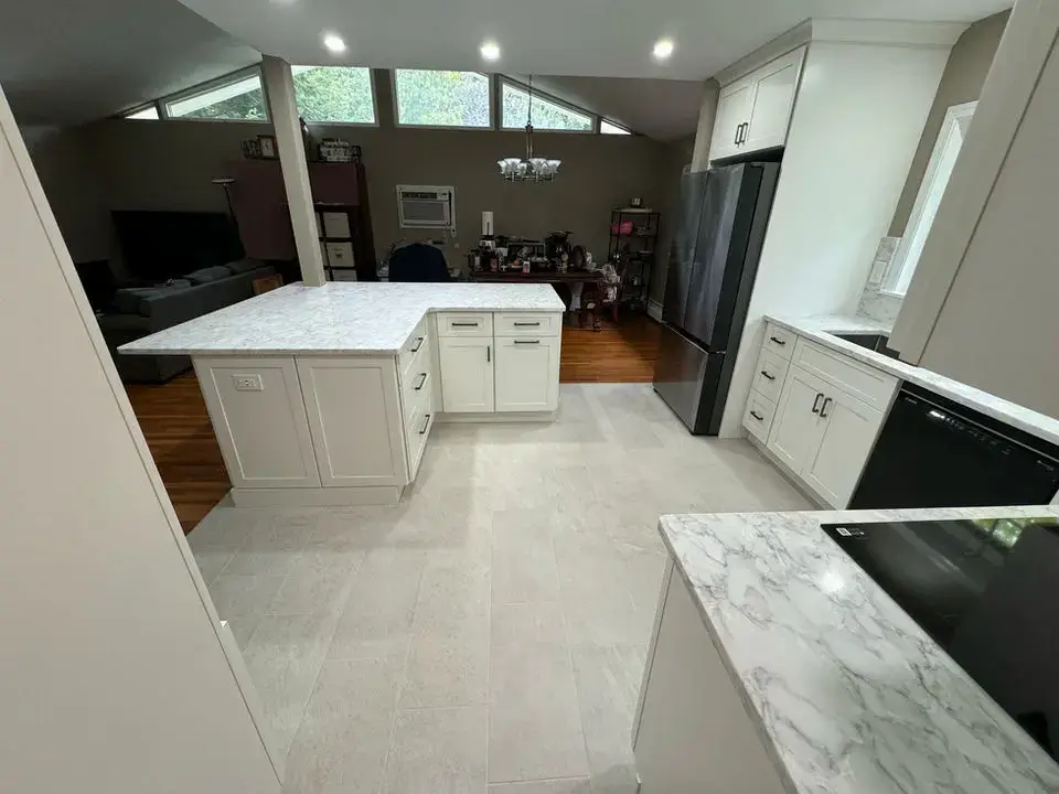 White kitchen renovation with island and pendant lighting by Skills Renovation.