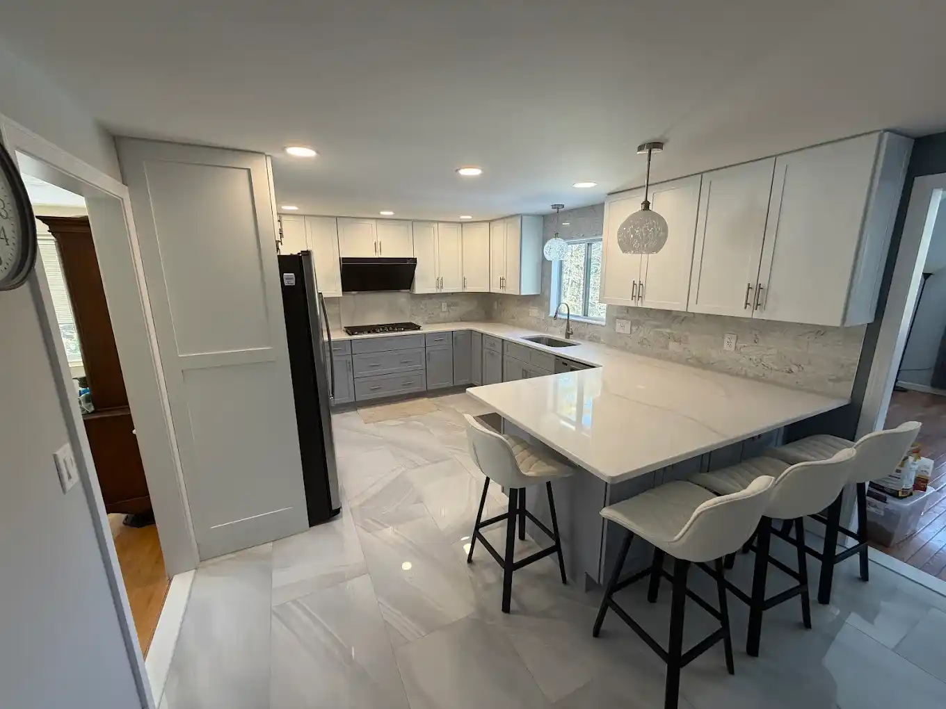 Modern kitchen remodel with white cabinets, gray peninsula base, and bar seating.