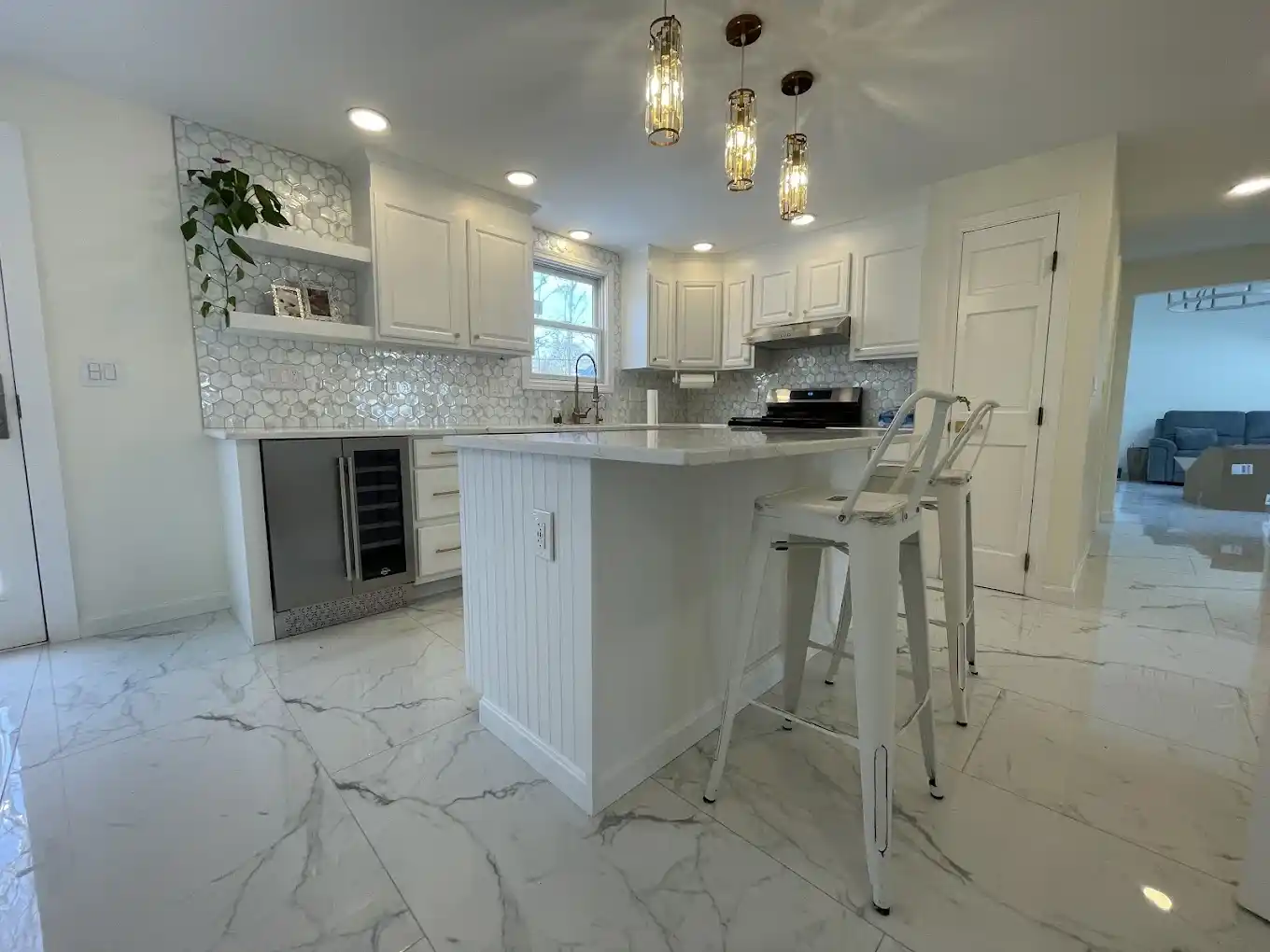 Kitchen remodel featuring white island, bar stools, and built-in beverage cooler.