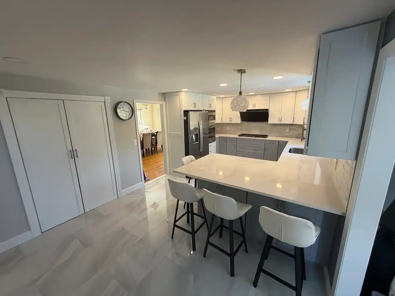 Spacious kitchen remodel showing island seating, white floor tiles, and open entryway.