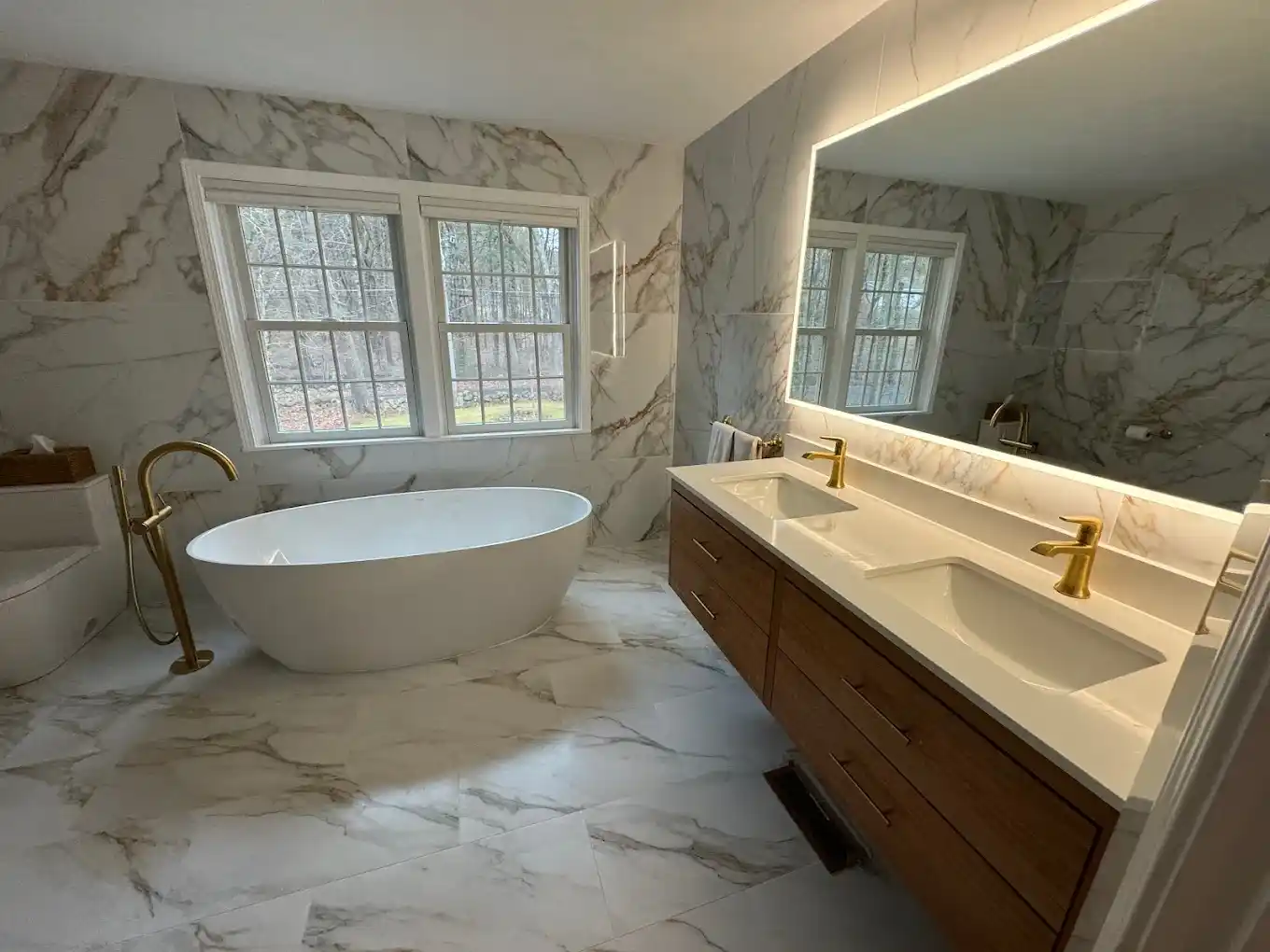 Luxury bathroom remodel with freestanding soaking tub, double vanity, and marble walls.