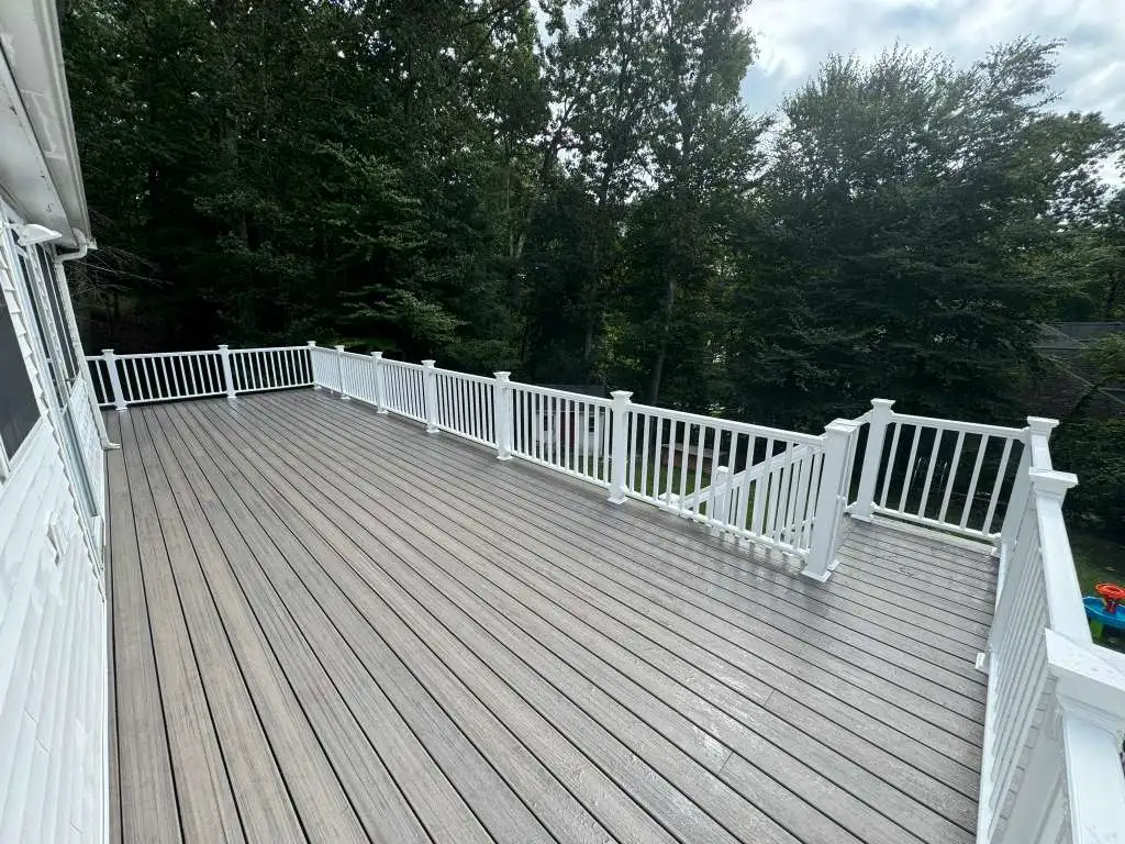 Large elevated composite backyard deck with gray boards and white railings.