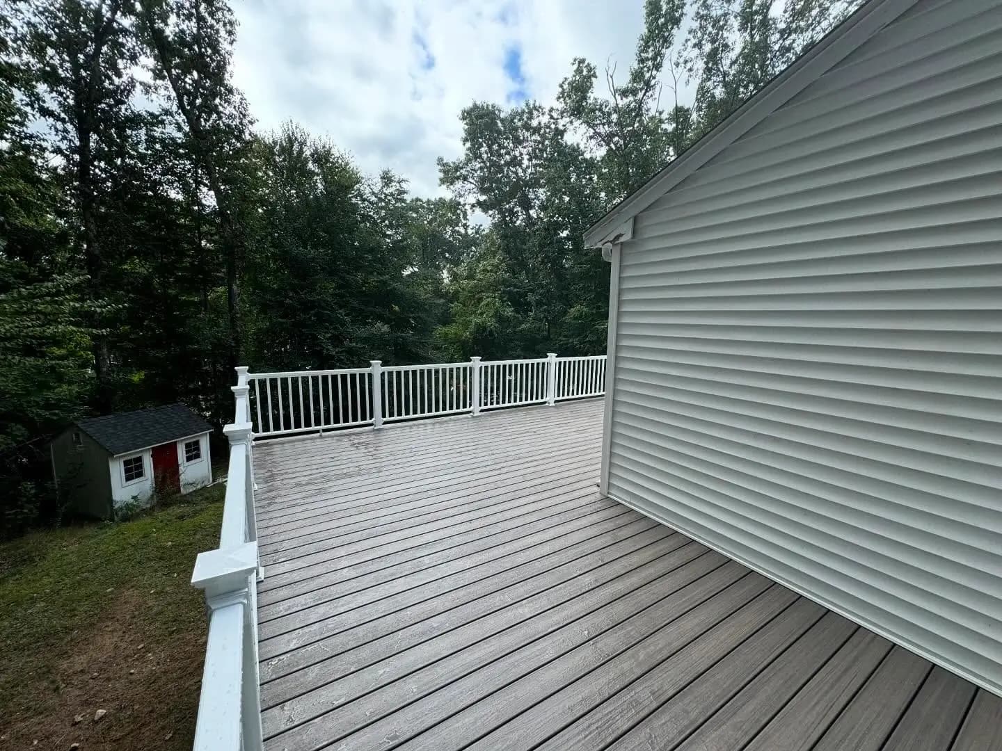 Large composite deck with white railings by Skills Renovation.