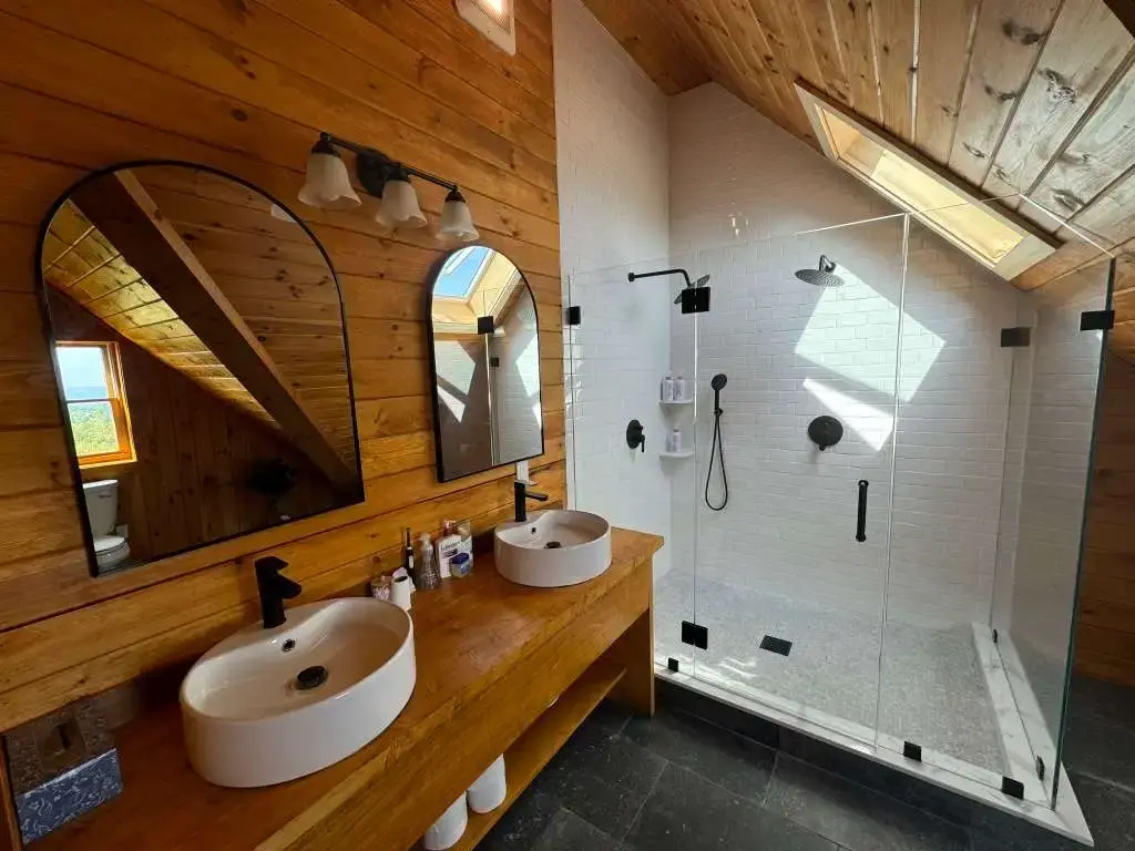 Double vessel sink vanity and arched mirrors in a rustic bathroom remodel.